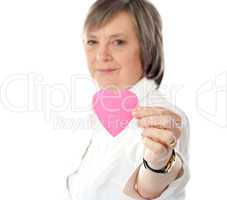 Focus on pink paper heart. Aged woman holding it