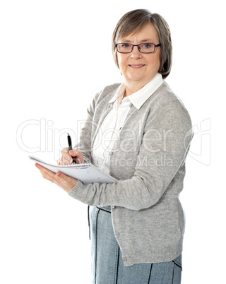 Aged woman writing on spiral notebook