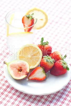 cocktail with ice,lemon, fig and strawberries on a plate