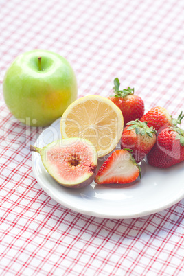 apple, lemon, fig and strawberries on a plate