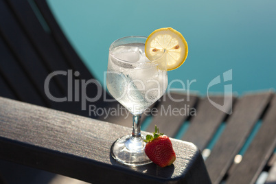 Swimming pool, lounge, a wine glass with ice, lemon and strawber