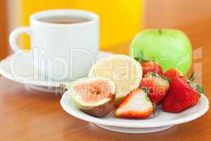cup of tea, apple, lemon, fig and strawberries on a plate