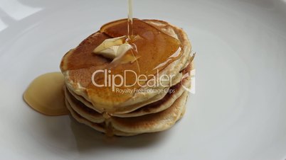 Pouring maple syrup on pancakes