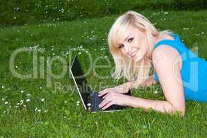 Smiling woman using her laptop on the grass
