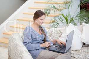 Woman sitting on a sofa while using a notebook