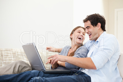 Couple laughing while typing on a computer