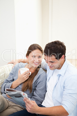 Couple sitting on a sofa while reading a newspaper