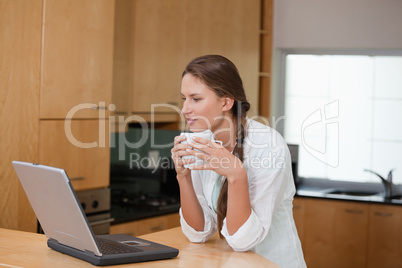 Woman holding a cup while looking at a computer