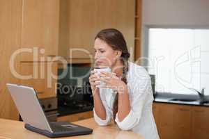 Woman holding a cup while looking at a computer