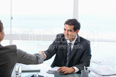 Businessman shaking hands with a client while sitting