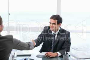 Businessman shaking hands with a client while sitting