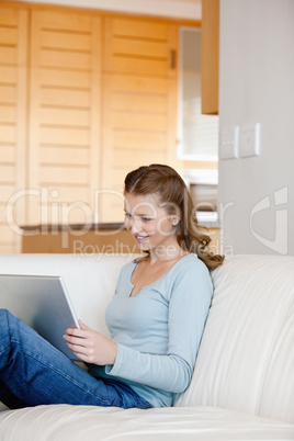 Woman sitting on a sofa while looking at laptop