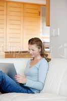 Woman sitting on a sofa while looking at laptop