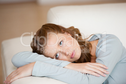 Woman crossing harms while lying on a sofa looking up