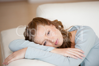 Woman lying on a sofa crossing her arms