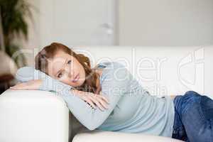 Woman lying on a sofa while crossing her arms