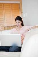 Woman using a laptop while sitting on a sofa