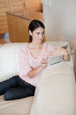 Woman sitting on a sofa while using a tablet computer