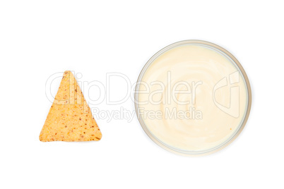 A bowl of dip and a nacho placed side by side