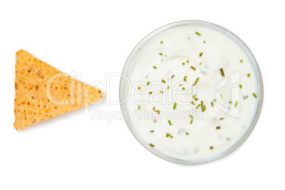 Bowl of dip with herbs beside a nacho