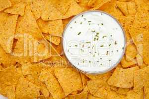 Bowl of dip with herbs surrounded by nachos