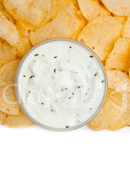 Close up of a bowl of white dip with herbs surrounded by nachos