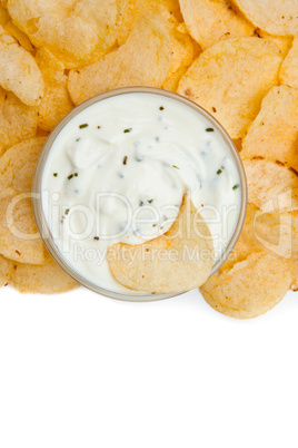 Close up of a bowl of dip with herbs and a nacho dipped in it