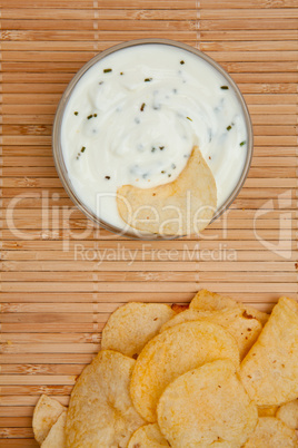 Close up of a bowl of  dip with herbs beside chips