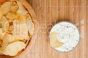 A bowl of chips and a bowl of dip side by side