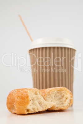 An half eaten doughnut and a cup of tea placed together
