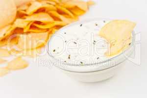Bowl of  dip with herbs beside chips