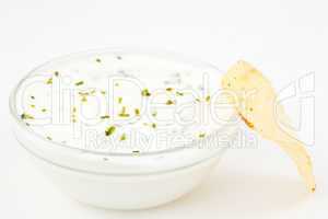 Bowl of white dip with herbs and a chips