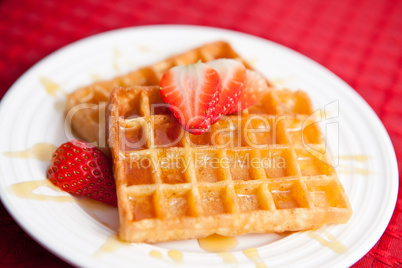 Waffles and half cut strawberry together in a white plate