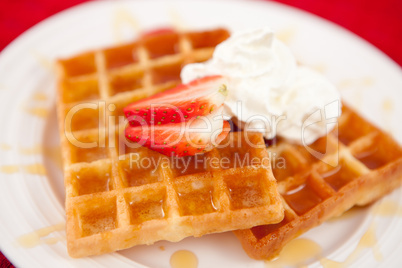 Waffles with whipped cream and strawberry and syrup