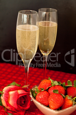 Top glasses of champagne with strawberries in a bowl and a rose