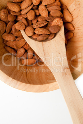 Wooden spoon with almonds in in a bowl