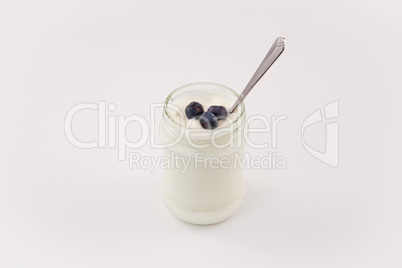 Pot of yoghurt with three blueberries