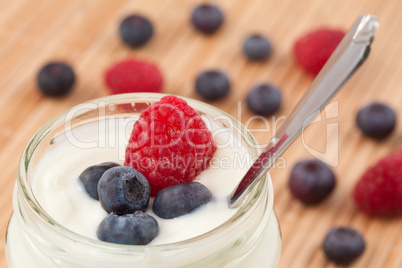 Close up of a pot yoghurt with blueberries and raspberry