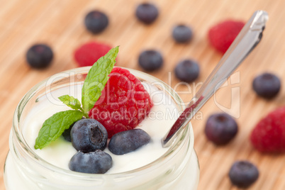 Close up of a pot yoghurt with mint blueberries and raspberry