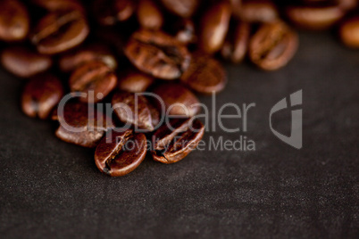 Dark blurred coffee seeds laid out together on a black table