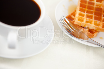 Waffles placed next to a coffee cup