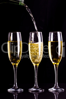 Two full glasses of champagne and one being filled