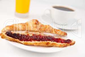 Coffee and orange juice behind a croissant