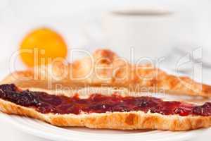 Coffee cup placed behind a croissant