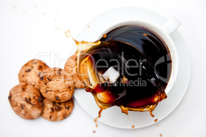 Sugar dropping in a cup of coffee with cookies