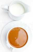 White cup of coffee next to a milk pot