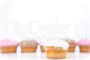 White muffin placed in front of a line of muffin with icing suga