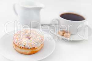 Doughnut milk and a cup of coffee on white plates with sugar and