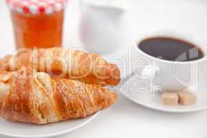 Croissants and a cup of coffee on white plates with sugar milk a