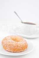 Doughnut with icing sugar and a cup of coffee with spoon on whit